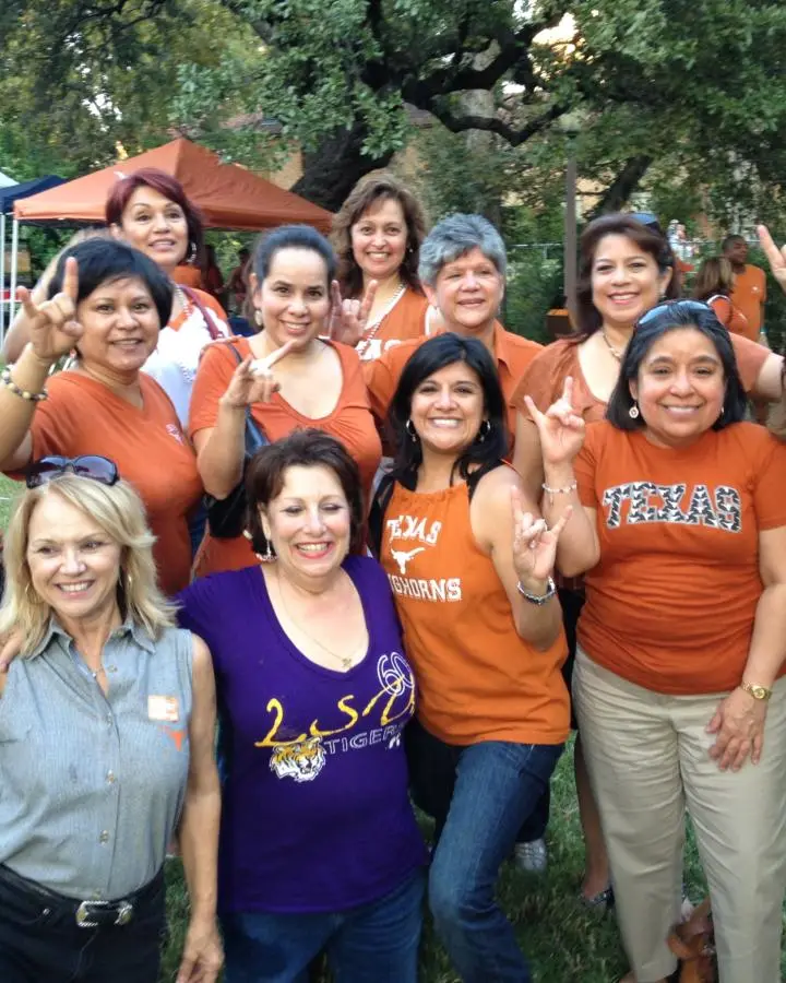 A group of members throwing the Hook ’em Horns sign at the tailgate