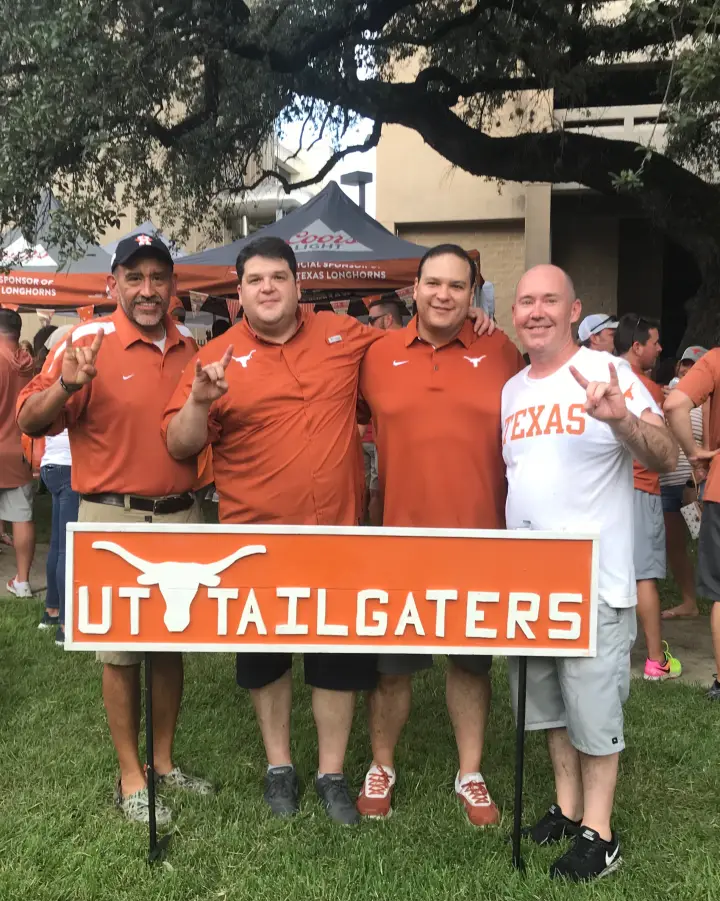 The club’s founders holding the UT Tailgaters sign on the lot