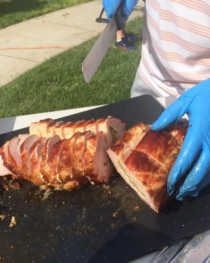 A member in gloves slicing a stuffed pork loin at the Chef’s Table