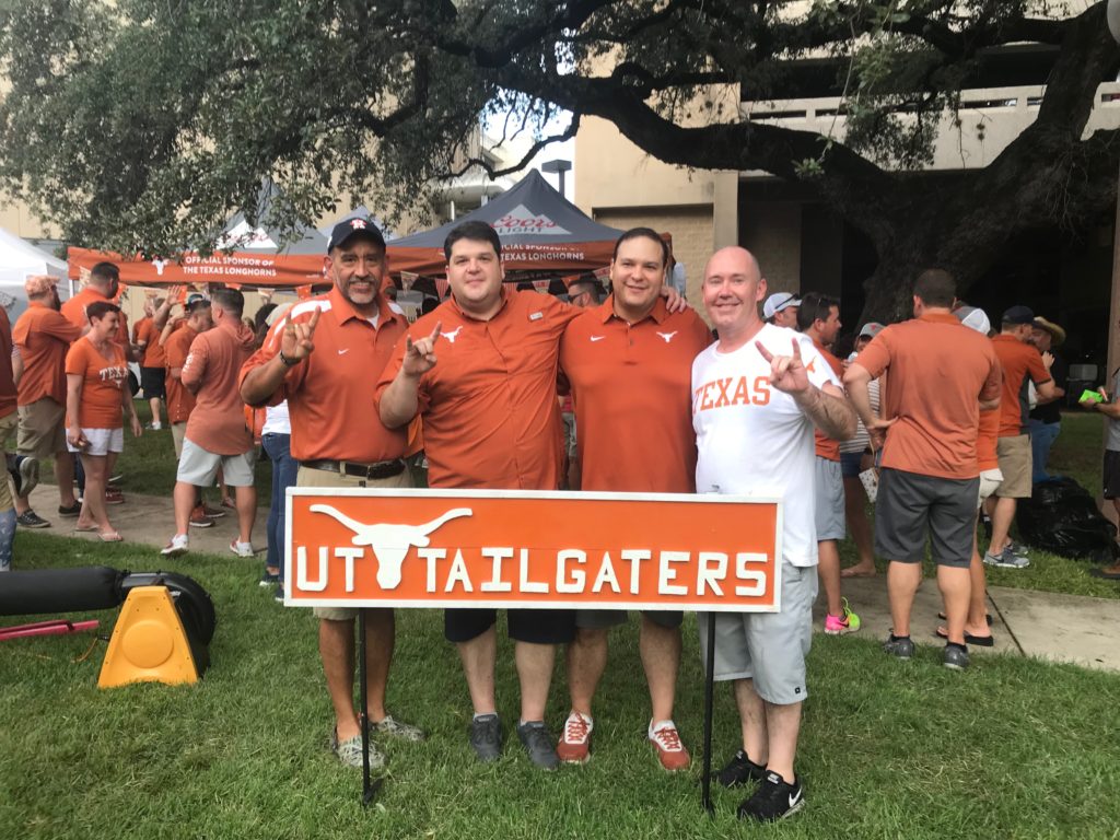 The founders posing with the UT Tailgaters sign at the tailgate